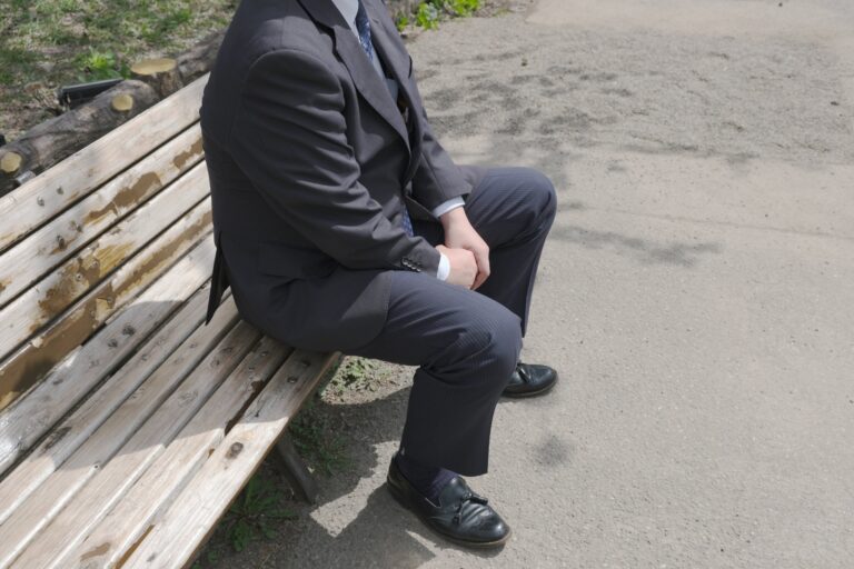 仕事に疲れて公園のベンチで考え込む男性のイメージ