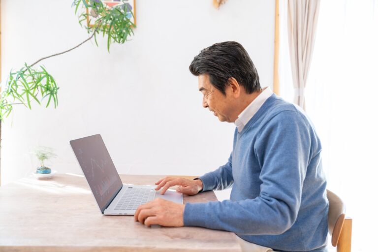 自宅でノートパソコンを使い小さく稼ぐ準備をする50代男性