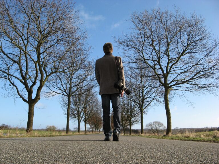 一本道を歩く人物の後ろ姿。元気なうちにできることを始め、未来へ向かって一歩を踏み出すイメージ