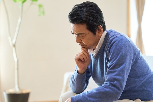 老後のためにいつまで我慢すればいいのか、自宅で考え込む50代の男性